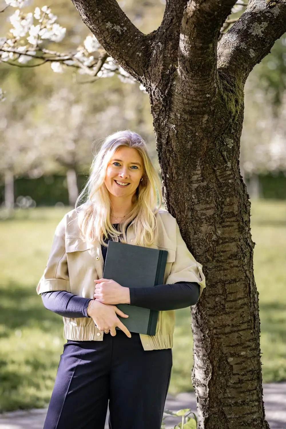 Martina Wutke mit Mappe an einem Baum